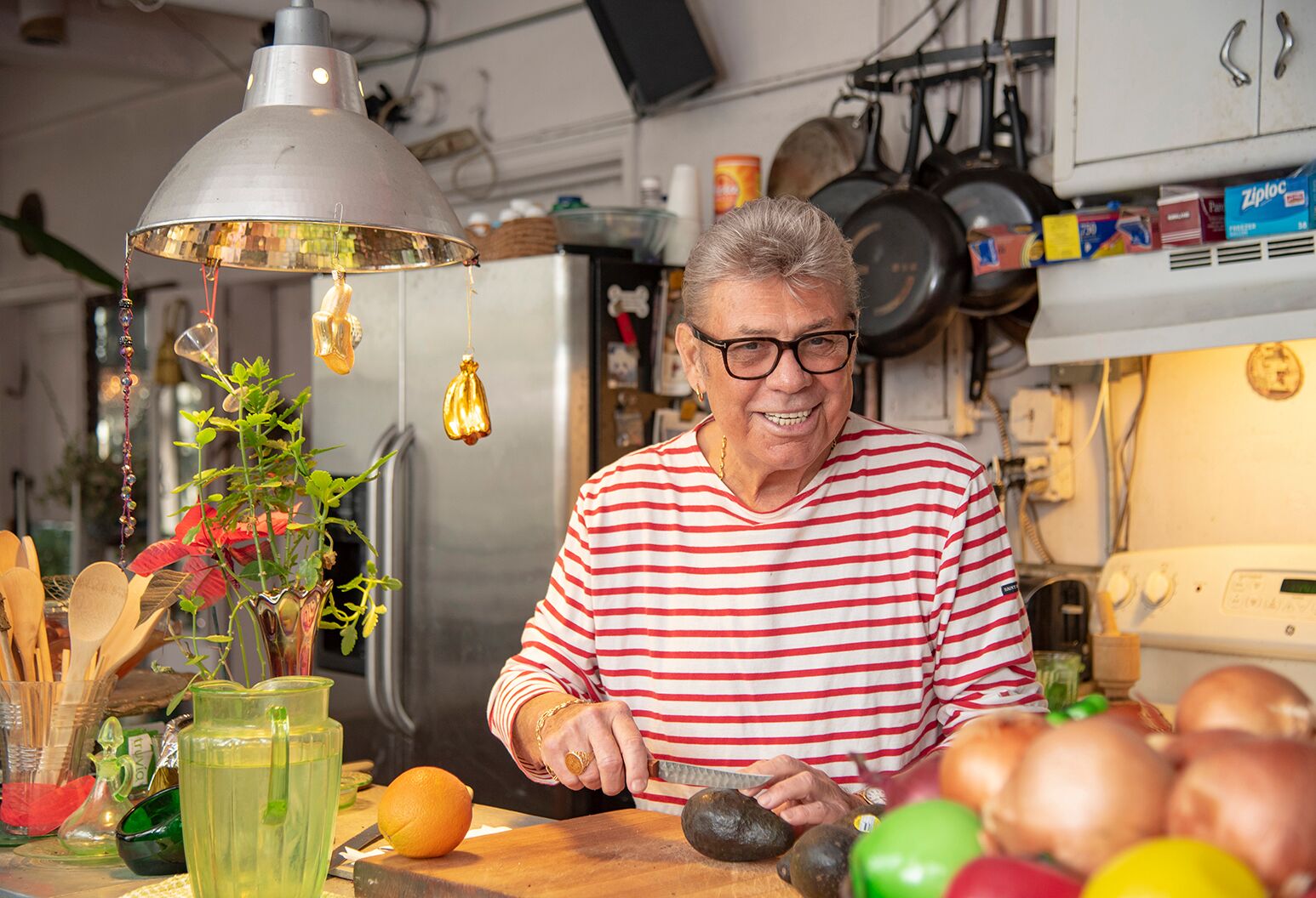 A smiling man in his late 70s slicing an avocado in his kitchen